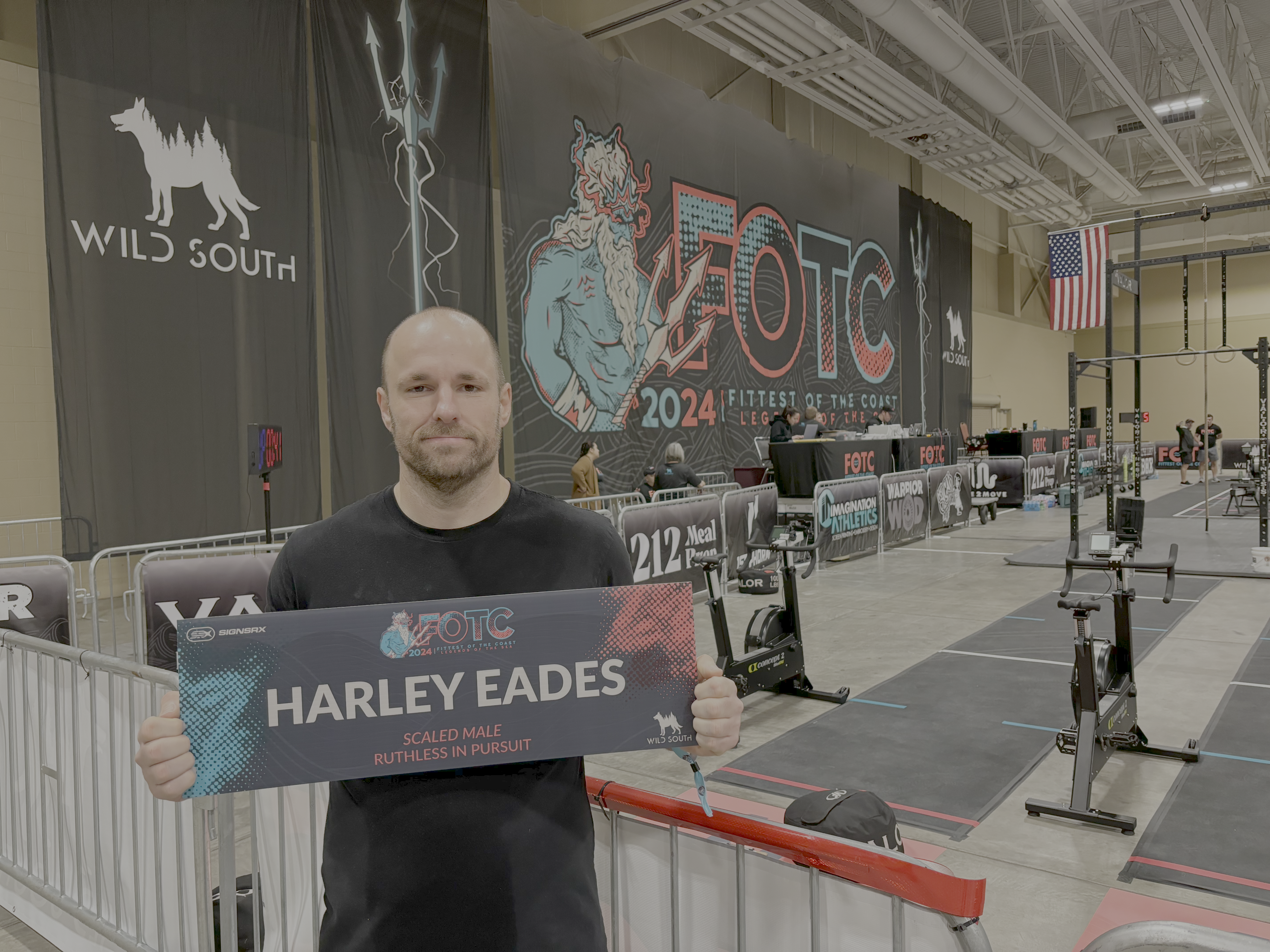 I am holding a sign with my name on it on the competition floor for Fittest of the Coast 2024.